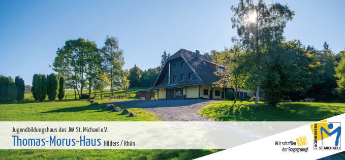 Grünfläche mit Bäumen und einem Gebäude im Hintergrund an einem sonnigen Tag.