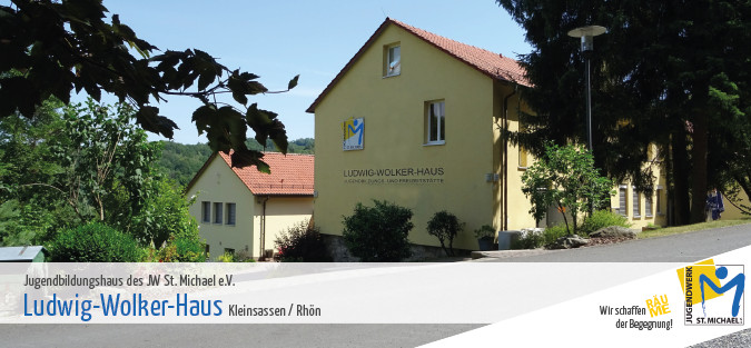 Gelbes Gebäude mit roten Dächern in grüner Umgebung.