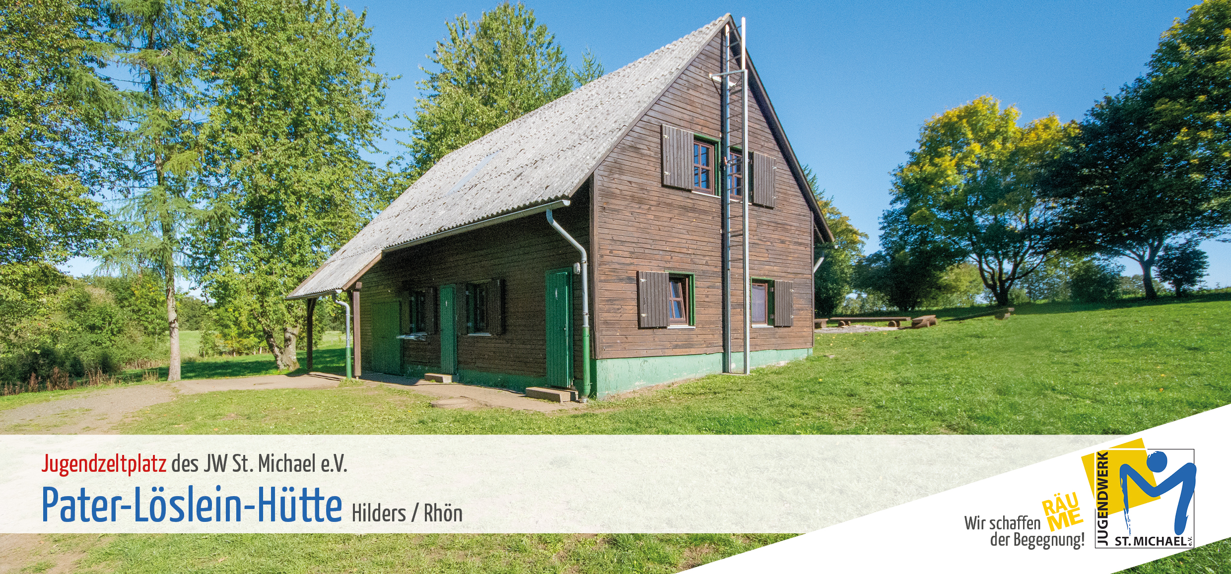 Kleine Holzhütte mit spitzem Dach auf einer Wiese.